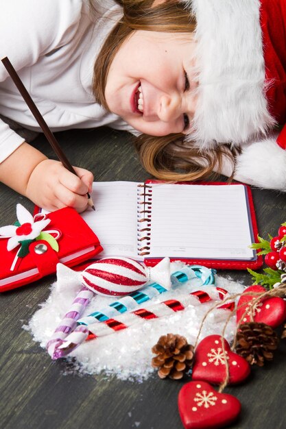 Foto chica feliz escribiendo en un libro en el suelo durante la navidad