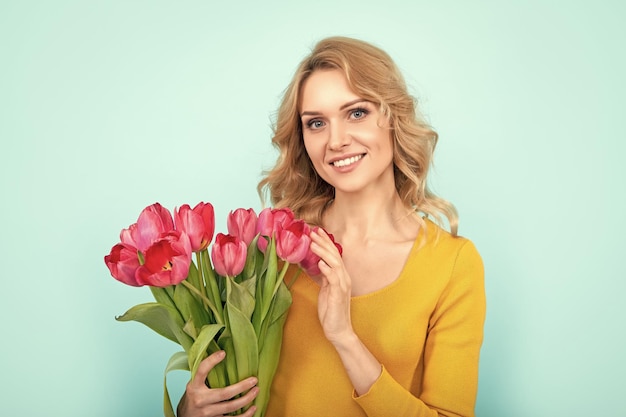 Chica feliz con flores de tulipán de primavera sobre fondo azul.