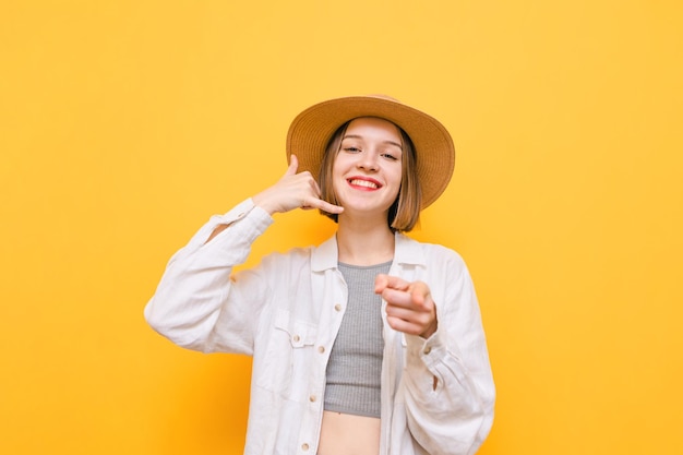 La chica feliz se para en un fondo amarillo y mira a la cámara con una sonrisa en la cara