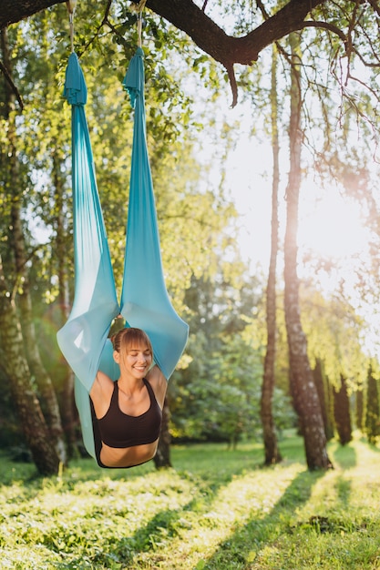 Chica feliz haciendo volar yoga ojos cerrados al aire libre