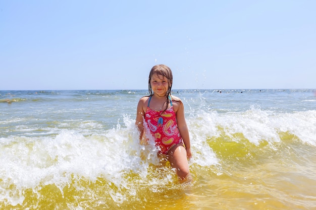 Chica feliz en un océano de playa tropical se divierte con splash