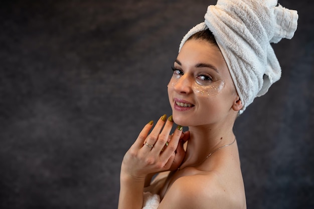 Chica feliz con parches en los ojos guiñando el ojo haciendo procedimientos antienvejecimiento aislados en negro