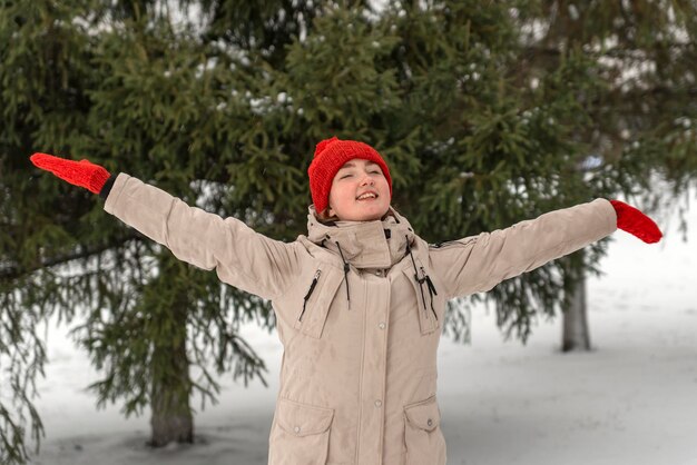 Foto chica feliz con ropa cálida de invierno disfruta de la naturaleza en el bosque de invierno mujer joven caminando en un parque cubierto de nieve