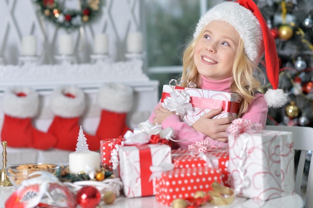 Chica feliz con sombrero de Santa sentado con regalos de Navidad