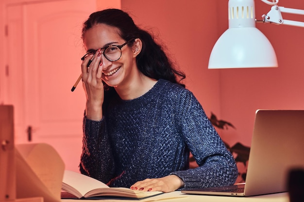 Una chica feliz y sonriente está sentada en la habitación mientras aprende una nueva lección.