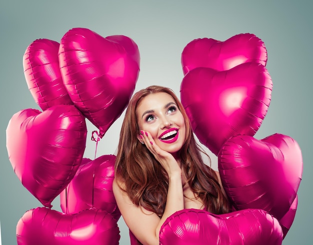Una chica feliz y sorprendida con globos rosados