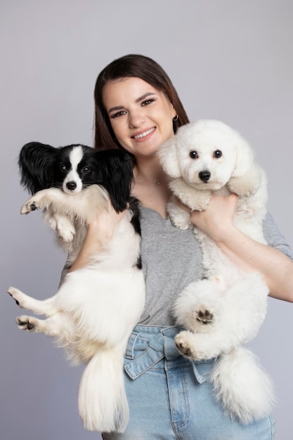 Chica feliz sosteniendo lindos perros bichon y papillon