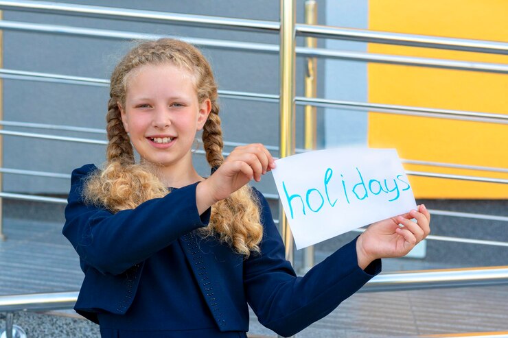 Chica feliz sosteniendo papel con las palabras Vacaciones Concepto Vacaciones escolares Chica de graduación en un uniforme alumno alumno erudito colegiala feliz