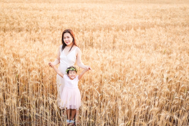 Chica feliz con su madre de pie en el campo de trigo