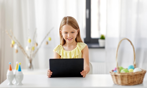 chica feliz con tablet PC y huevos de Pascua en casa