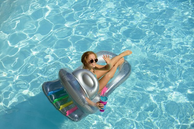 Chica feliz verano en traje de baño chica en vacaciones de verano mujer en piscina en colchoneta inflable