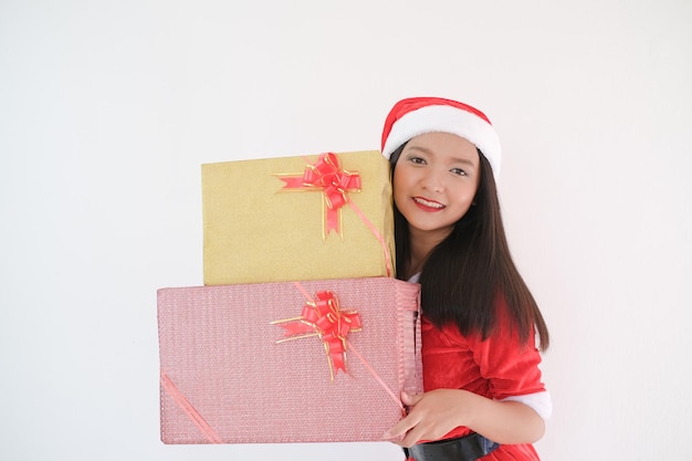 Chica feliz en vestido de santa claus con caja de regalo sobre fondo blanco en la fiesta de Navidad