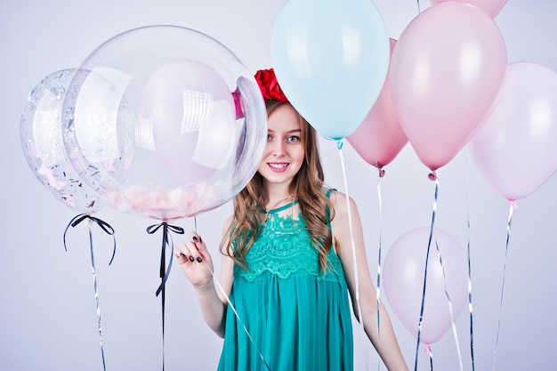 Chica feliz en vestido verde turquesa y corona con globos de colores aislados en blanco Celebrando el tema del cumpleaños