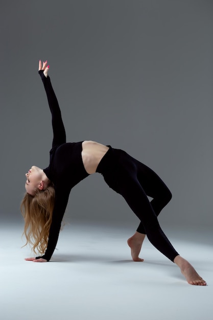 Una chica con una figura deportiva hace ejercicios de gimnasia para estirar