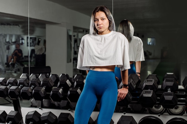 Chica fitness deportivo está posando en las pesas en el gimnasio