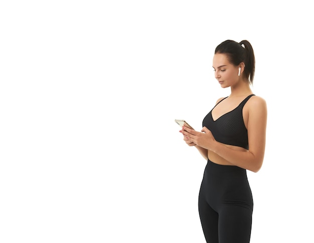 Chica fitness en entrenamiento en ropa deportiva tiene un teléfono inteligente en sus manos