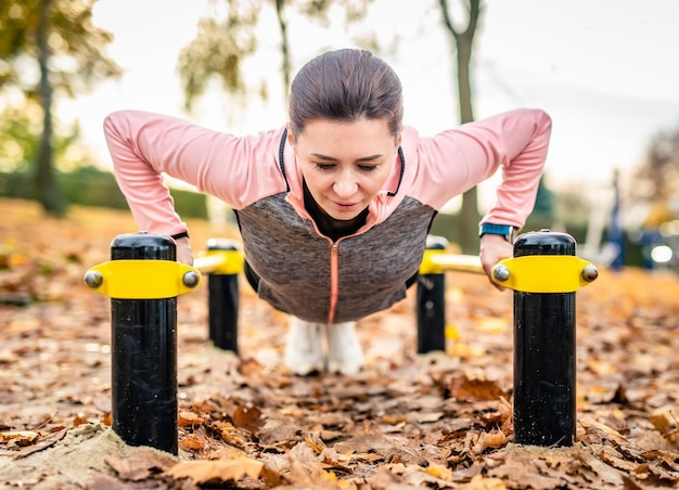 Foto chica fitness haciendo flexiones outdoots en otoño mujer joven haciendo ejercicio en el parque