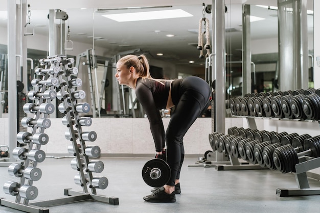 Chica fitness levantando mancuernas en el gimnasio