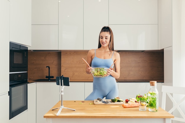 chica fitness preparando ensalada en la cocina