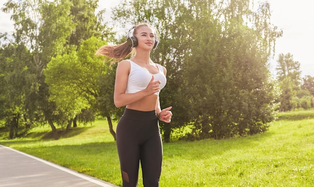 Chica fitness en ropa deportiva corre por el parque soleado por la noche Estilo de vida saludable