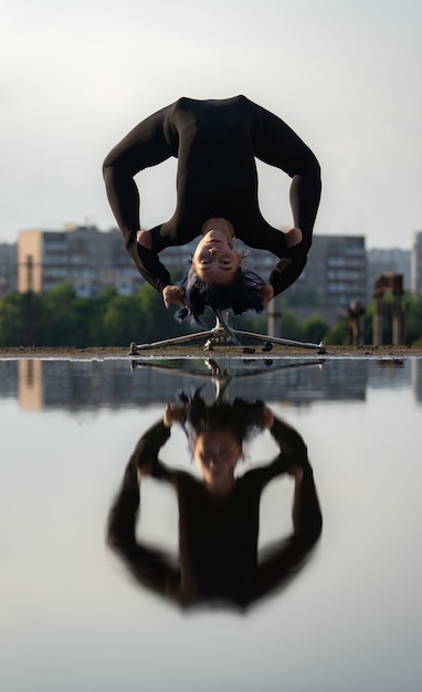 Chica flexible doblando la espalda boca abajo con reflejo en el agua. individualidad, concepto de creatividad