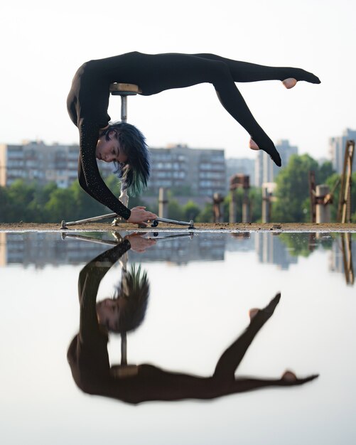 Chica flexible y en forma doblando su espalda boca abajo con reflejo en el agua. Concepto de individualidad, creatividad y destaque.