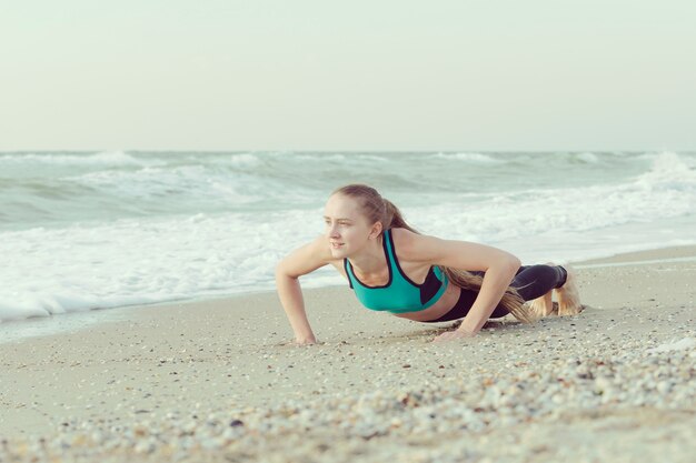 Chica flexiones en la playa, olas