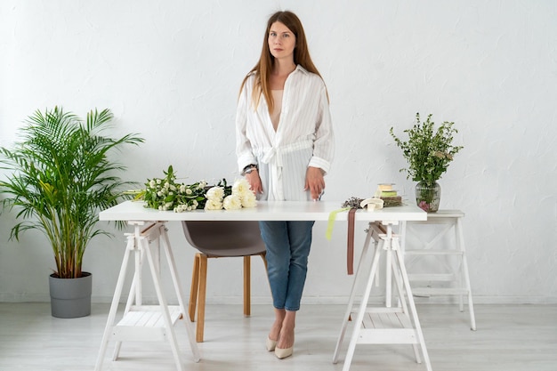 Chica florista prepara un lugar de trabajo para la posterior colección de un ramo Flores blancas Floristería en el trabajo Clase magistral de educación cursos de floristería