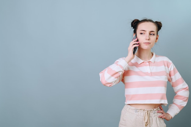 Una chica de fondo azul suave con un peinado divertido está hablando por teléfono con incredulidad