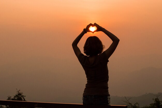 Chica en forma de corazón al atardecer.