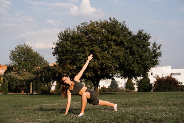 Chica en forma entrenando sobre hierba verde en el parque Entrenamiento al aire libre Estilo de vida deportivo de mujer joven activa