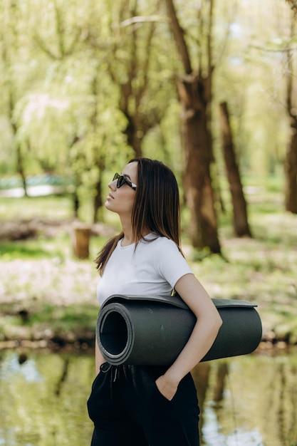 Chica en forma vestida con ropa deportiva con una botella de agua y una colchoneta de entrenamiento al aire libre Estilo de vida deportivo