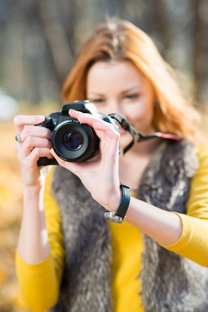 Foto chica fotógrafa con una cámara hace una sesión de fotos en el parque de otoño