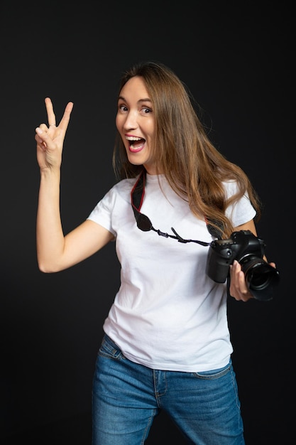 Chica fotógrafa con una cámara sonriendo sobre un fondo negro