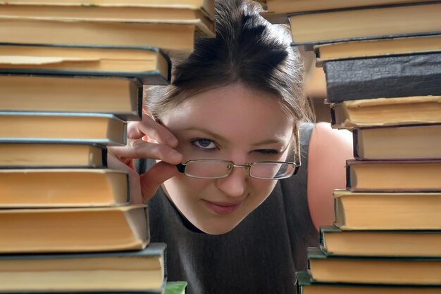 Chica con gafas con libros antiguos en la biblioteca.