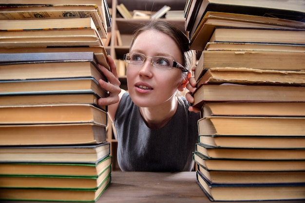 La chica de las gafas entre los libros antiguos de la biblioteca.