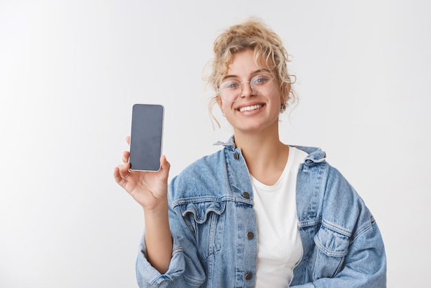 chica con gafas muestra la pantalla del teléfono inteligente