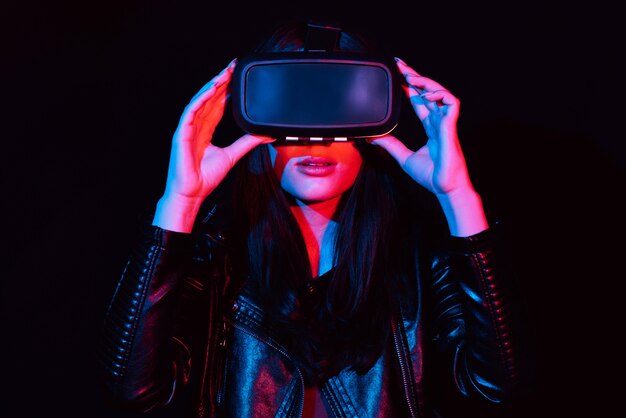 Chica con gafas de realidad virtual moderna sobre un fondo negro