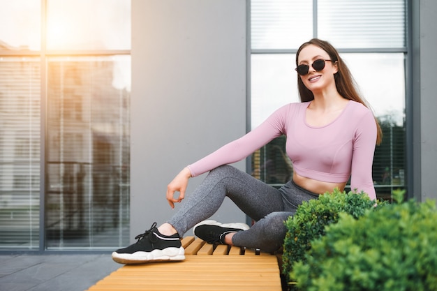 Foto chica con gafas se sienta en un banco