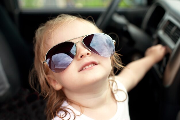 Chica con gafas de sol sentada en el coche