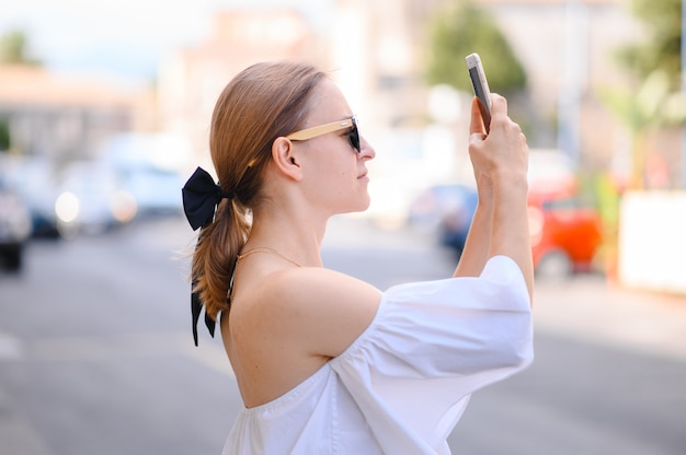 Chica con gafas de sol toma fotos en el teléfono inteligente