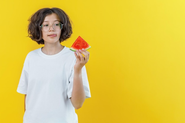 Chica con gafas sostiene en su mano un trozo de sandía sobre fondo de color