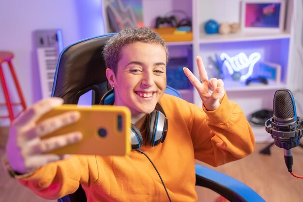 Chica gamer con corte de pelo corto tomando una selfie jugando juegos en línea y transmisión