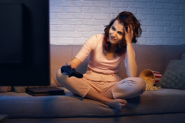 Chica gamer molesta jugando videojuegos en la consola en casa