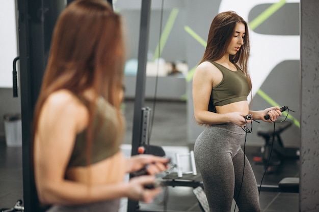 Chica en el gimnasio con saltar la cuerda delante del espejo