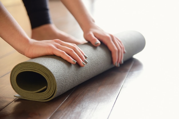 Chica gira estera de yoga después de clase