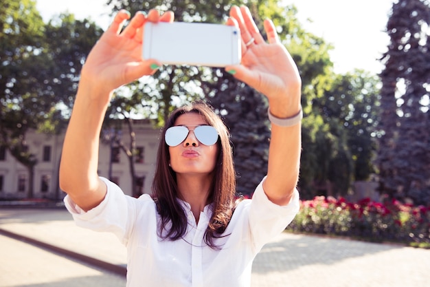 Chica glamorosa haciendo un selfie con su smartphone al aire libre