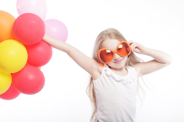 Chica con globos y gafas de sol naranjas.