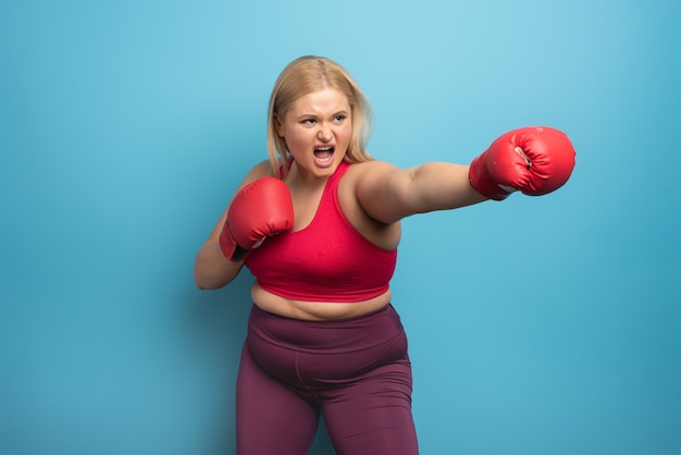 Chica gorda en gimnasio hace boxeo.