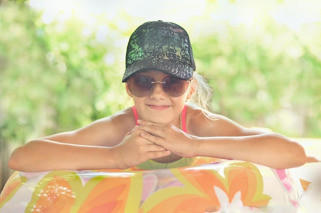 Chica con gorra y gafas en un anillo inflable